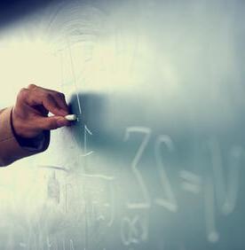 Teacher drawing math symbols on chalk board